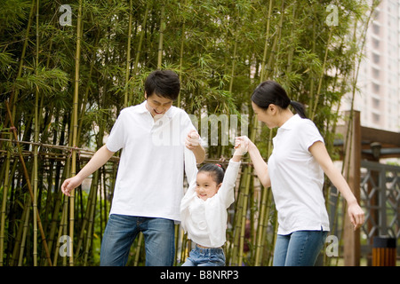 Young parent carrying up daughter by their arms outdoors Stock Photo