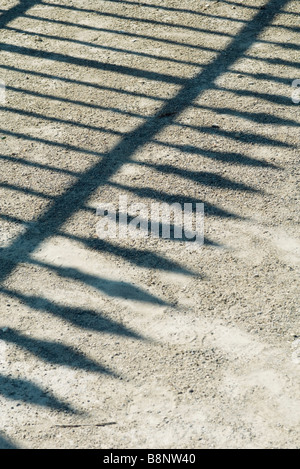 Shadow of wrought iron fence on gravel Stock Photo