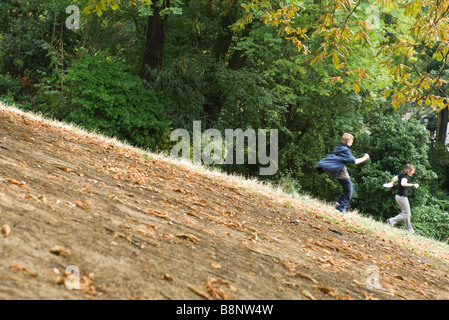 People running down hill in park Stock Photo