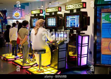 arab man playing on slot machine in amusement arcade, dubai, uae Stock Photo