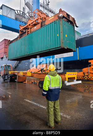 worker supervising container uploading at dock Stock Photo