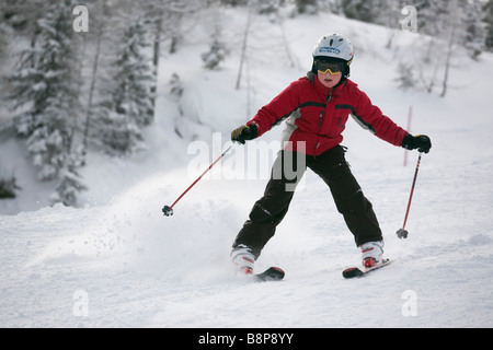 Young novice skier doing snowplough turn skiing downhill with fresh snowfall on ski slope piste in Austrian Alps Austria Europe Stock Photo