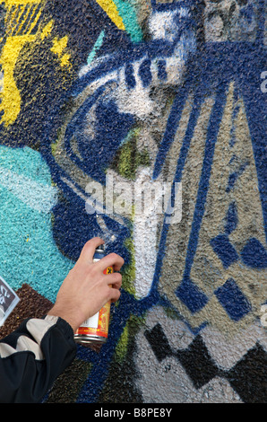 Hand of Graffiti artist using spray paint can and painting wall mural ...