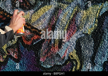 Hand of Graffiti artist using spray paint can and painting wall mural ...