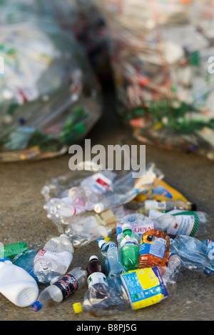 Crushed plastic bottles on ground, garbage bags in background Stock Photo