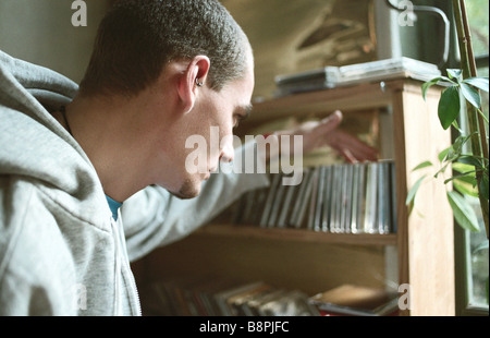 Young man selecting CD from collection on shelf Stock Photo