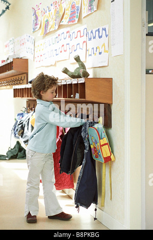 Girl hanging up jacket in school cloak room Stock Photo