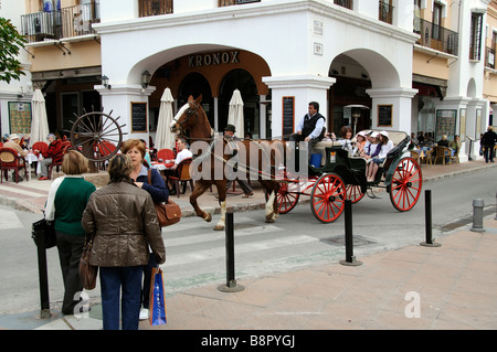 Horse drawn taxi and customers ride through the town centre of Nerja in southern Spain Stock Photo
