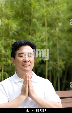 Senior man in prayer position outdoors Stock Photo