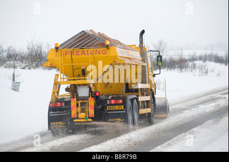 Gritter lorry with snow plough fitted to the front clearing the roads of snow in rural Leicestershire England Stock Photo