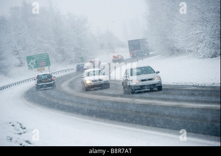 Cars driving slowly on a snowy road during the morning rush hour in winter in England Stock Photo
