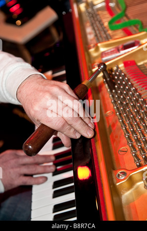 Detail of the hands of a man piano tuner tuning a grand piano before a concert, UK Stock Photo