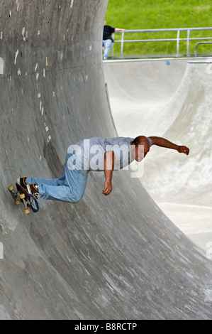 Middle Age Man Riding Skateboard through Full Pipe at the Louisville Extreme Skate Park in Louisville Kentucky Stock Photo