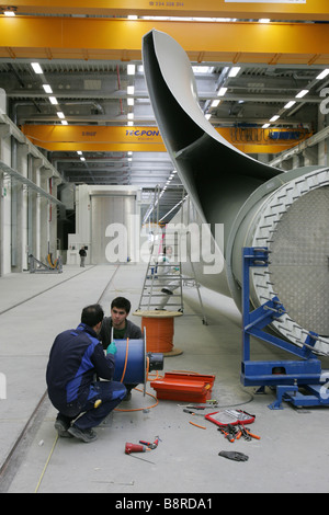 Workers next to a giant wind turbine blade at the factory VentoMoinho at Viana do Castelo, Portugal. Stock Photo