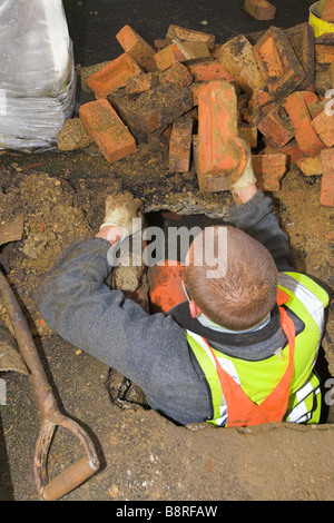 Workman removing bricks from a hole Stock Photo
