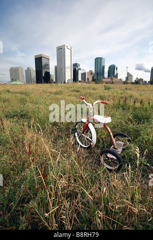 Old rusted child's tricycle in open field with city skyline behind Edmonton Alberta Canada Stock Photo