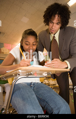 african american middle school teacher helps teenage student solve a math problem in the classroom, southwestern united states Stock Photo