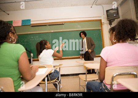 smiling middle school student interacts with student answering a question in a classroom Stock Photo