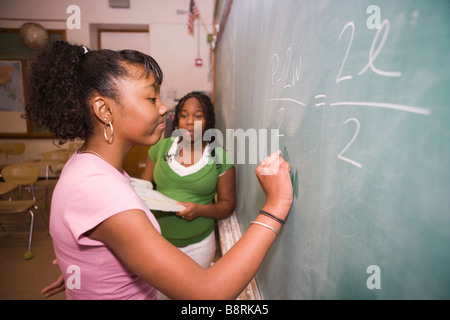 two middle school students practice algebra problem on the blackboard, testing eachother on math skills Stock Photo