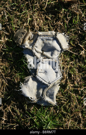 part of one old damaged leather football in field Stock Photo