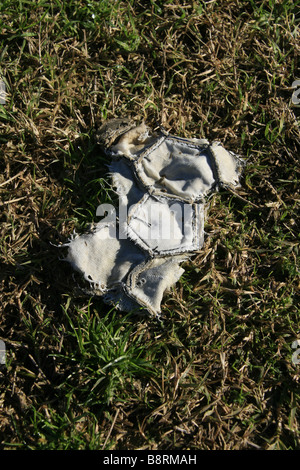 part of one old damaged leather football in field Stock Photo