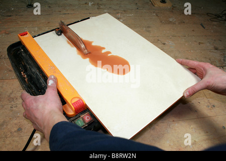 man using a tile cutting machine to cut a ceramic wall tile Stock Photo