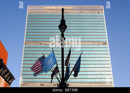 Lamp post with UN and US flags in front of the glass facade of the United Nations headquarters, UNO, New York, USA