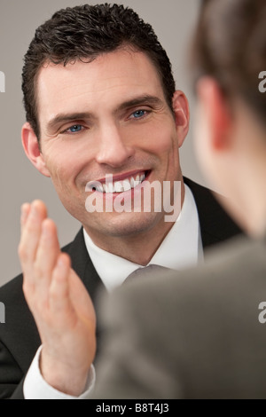 A young male executive explains to his female colleague who is out of focus in the foreground Stock Photo