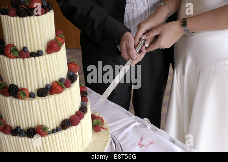 close up of a couples hand cutting their wedding cake Stock Photo