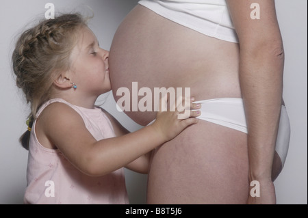 Child kissing mothers abdomen Kind kuesst Mutters Bauch Stock Photo