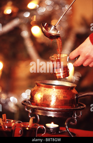 Hand pouring up mulled wine in a cup. Stock Photo
