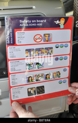 Interior cabin Airbus A340 - 600 passenger holding a safety onboard instruction card Stock Photo