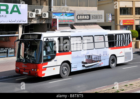 Dubai public transport single deck bus service driving along shopping street route run by the Roads and Transport Authority United Arab Emirates UAE Stock Photo