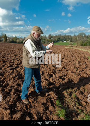 FARMER EXAMINING SOIL IN PLOUGHED FIELD Stock Photo