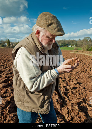 FARMER EXAMINING SOIL IN PLOUGHED FIELD Stock Photo