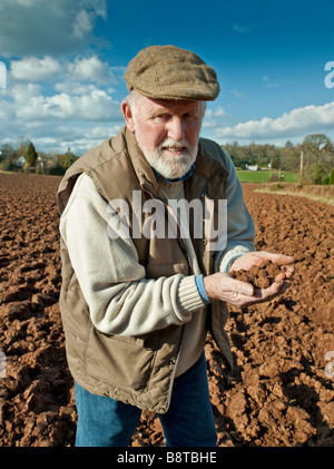 FARMER EXAMINING SOIL IN PLOUGHED FIELD Stock Photo