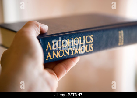 a person holding 'The Big Book' of Alcoholics Anonymous Stock Photo