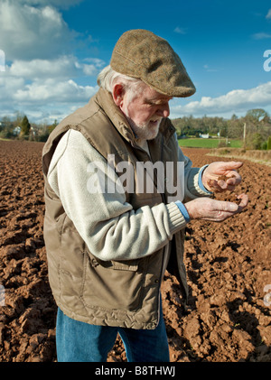 FARMER EXAMINING SOIL IN PLOUGHED FIELD Stock Photo