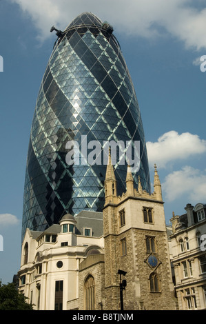 The Gherkin building with an old church in the foreground Stock Photo