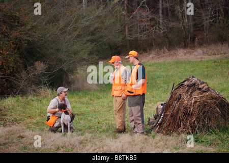 TWO UPLAND BIRD HUNTERS TAKE A BREAK WITH GUIDE AND DOG SHOT GUNS AND HARVESTED GAME GEORGIA