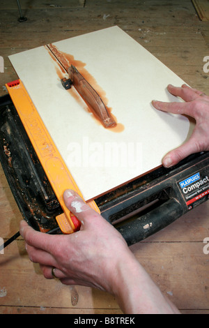 man using a tile cutting machine to cut a ceramic wall tile Stock Photo