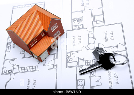 A model home and house key on architectural floor plans for an extension Stock Photo