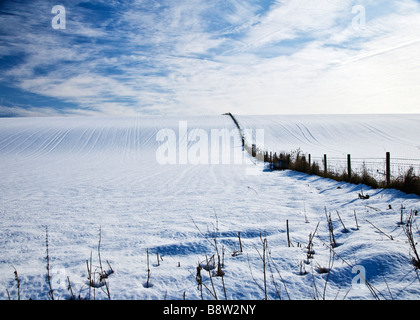A sunny snowy winter landscape view or scene showing a snow covered field and cirrus cloud formation in a blue sky Stock Photo