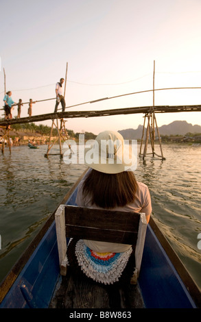 Laos, Vientiane Province, Vang Vieng, Nam Song River, woman on boat, bridge, tourists. Stock Photo