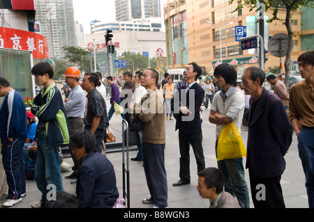 People gather to watch the latest soap opera on TV sets on display in a big electronic department store. Stock Photo