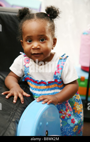 1 year old girl pulling herself up into the standing position - learning to walk Stock Photo