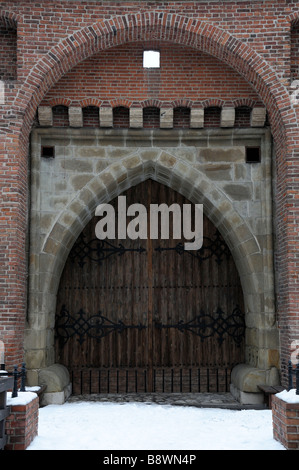snow covered path leading to the closed shut entrance gate door doorway gateway of the Great Barbican, Krakow, Poland Stock Photo