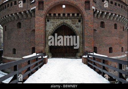 snow covered path leading to the closed shut entrance gate door doorway gateway of the Great Barbican, Krakow, Poland Stock Photo