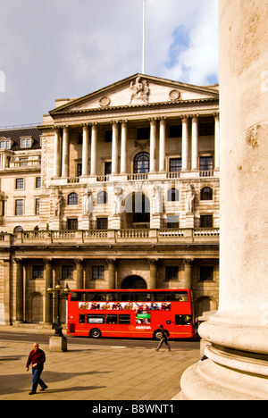 Red London bus driving past Bank of England building, UK Stock Photo