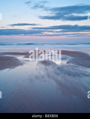 The colours of sunset reflected in the wet sands of Alnmouth beach on the Northumberland coast, England Stock Photo